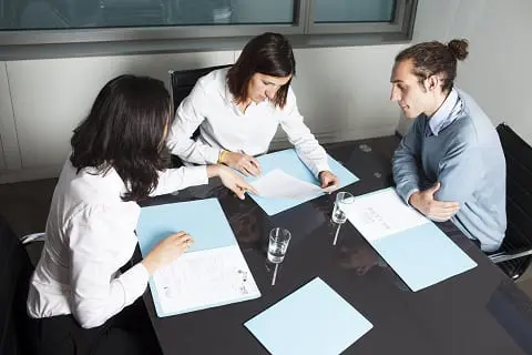 Couple reviewing paperwork with Realtor. 