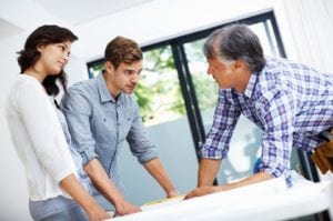 Young couple discussing home plan on blueprint with architect