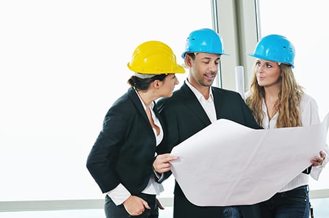 young arhitect group in big bright modern new apartment looking blueprints and building plans