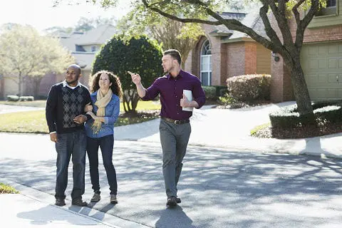 Realtor showing a home to a couple in a neighborhood. 