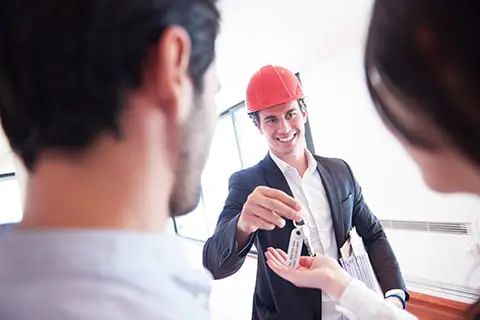 Realtor handing a couple their new house keys.