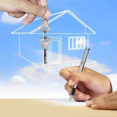 Close up image of hand holding keys and someone signing a contract.
