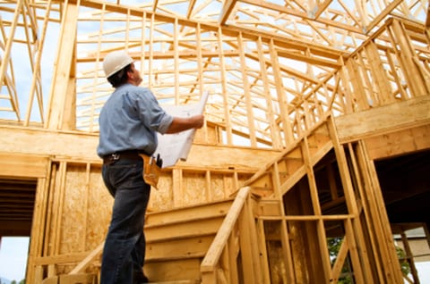 Builder looking a house plans inside a construction site.