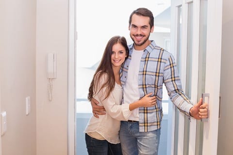 Millennial couple opening front door.