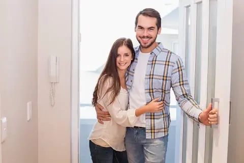 Millennial couple opening front door.