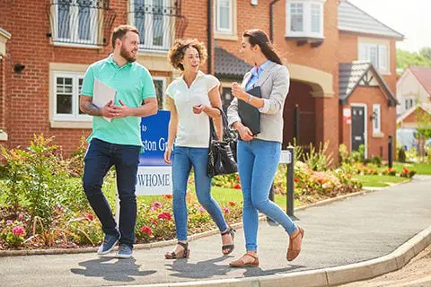 Couple with a Realtor walking in front of model home. 